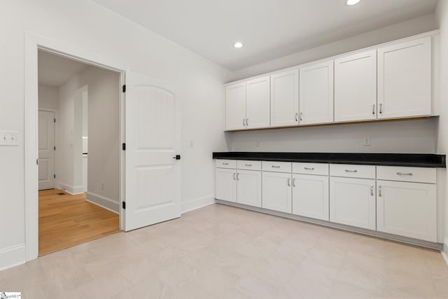 kitchen with baseboards, white cabinets, and recessed lighting