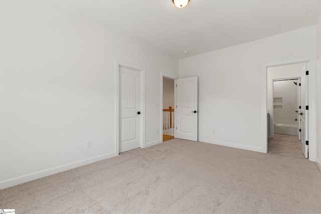 unfurnished bedroom with baseboards, connected bathroom, and carpet