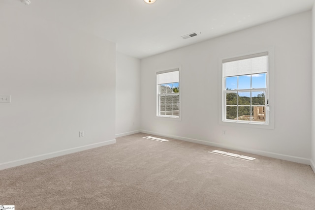 unfurnished room with visible vents, baseboards, and light colored carpet