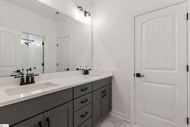 bathroom featuring marble finish floor, double vanity, a sink, and baseboards