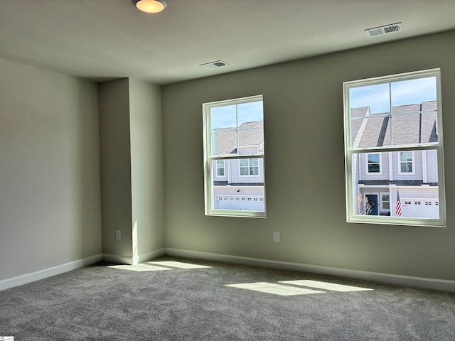 spare room with carpet flooring, baseboards, visible vents, and a wealth of natural light