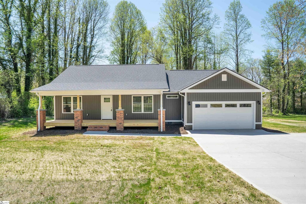 ranch-style home with a garage, a front lawn, concrete driveway, and covered porch
