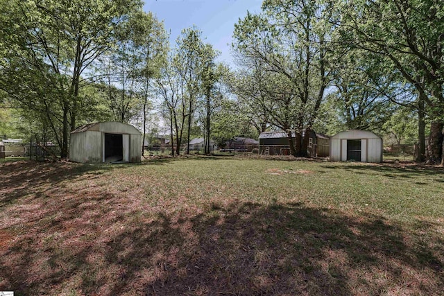 view of yard with fence, an outbuilding, and a storage unit