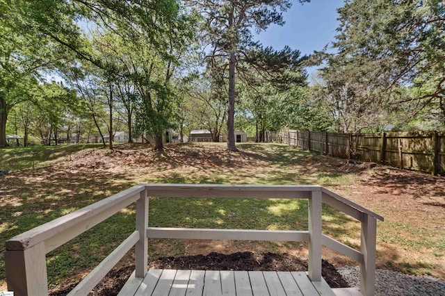 wooden deck featuring an outbuilding, fence, and a lawn
