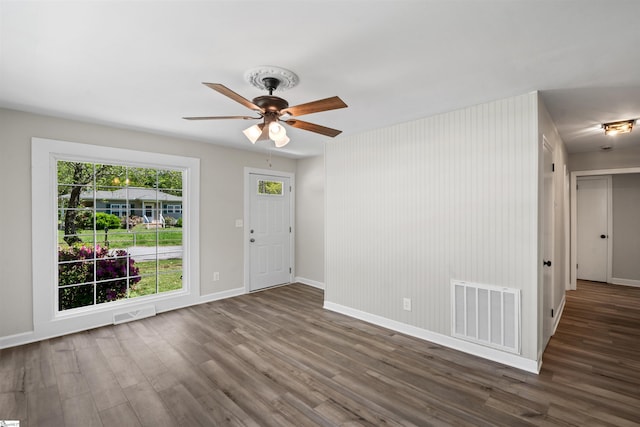 interior space with wood finished floors, baseboards, a ceiling fan, and visible vents
