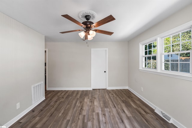 empty room featuring visible vents, baseboards, a ceiling fan, and wood finished floors