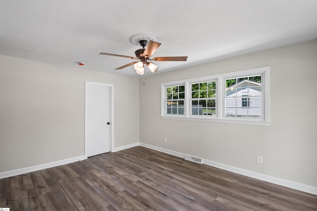 spare room featuring dark wood-type flooring, baseboards, a ceiling fan, and visible vents