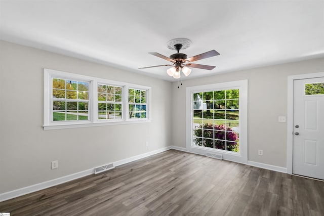 unfurnished room with ceiling fan, visible vents, baseboards, and wood finished floors