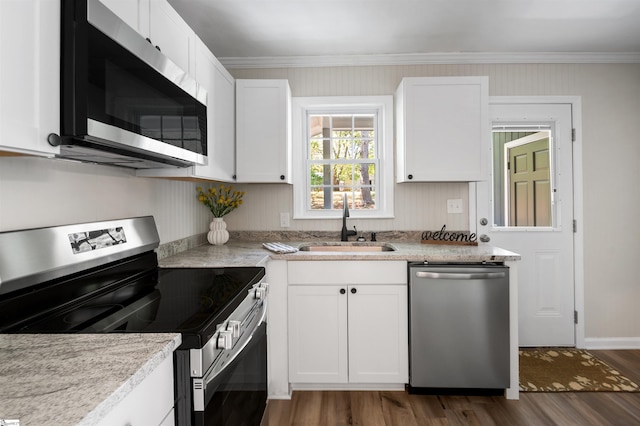 kitchen featuring crown molding, dark wood-type flooring, white cabinetry, a sink, and stainless steel appliances
