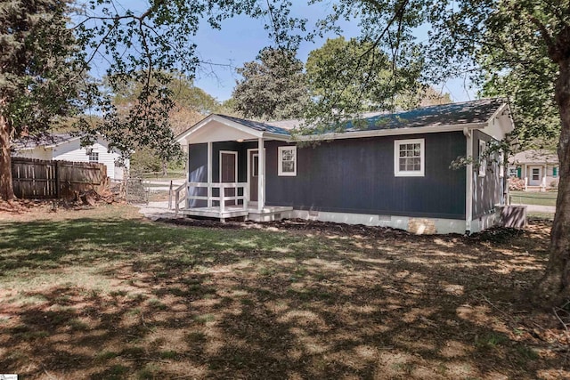 rear view of property with crawl space, fence, and a lawn