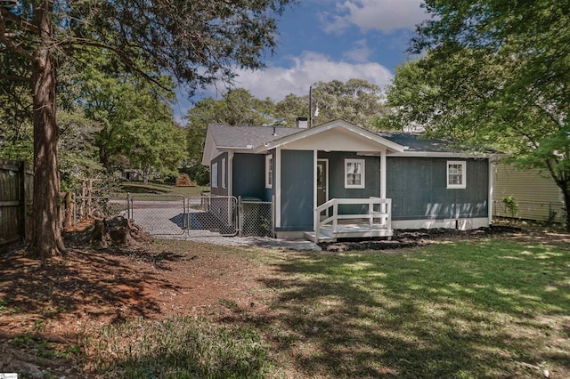 rear view of property featuring fence, a gate, and a lawn