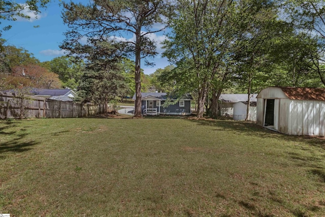 view of yard featuring an outbuilding, fence, and a shed