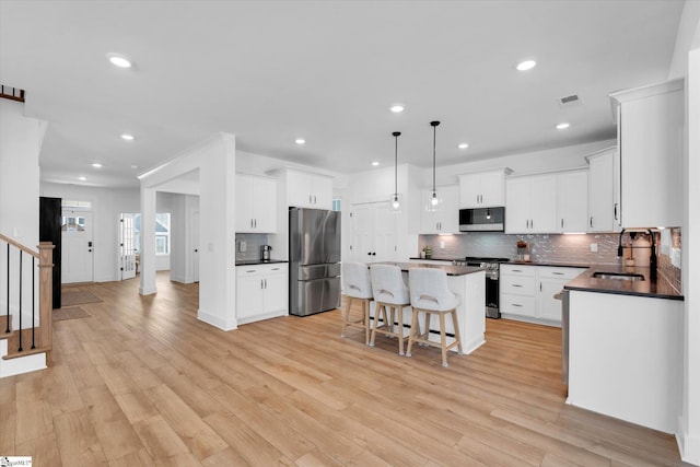 102 Moorish Cir, Simpsonville, SC 29681 - kitchen featuring a breakfast bar, dark countertops, a kitchen island, appliances with stainless steel finishes, and a sink
