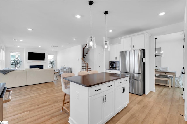 102 Moorish Cir, Simpsonville, SC 29681 - kitchen featuring light wood-type flooring, freestanding refrigerator, dark countertops, and a kitchen breakfast bar