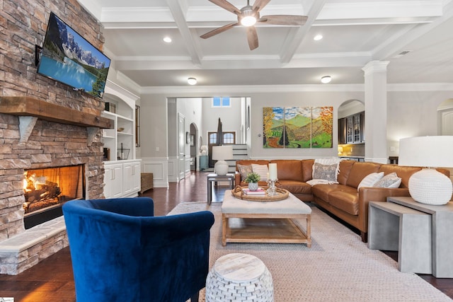 living area featuring a stone fireplace, beam ceiling, crown molding, and coffered ceiling
