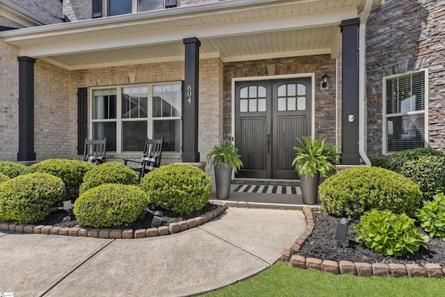 view of exterior entry featuring brick siding and a porch