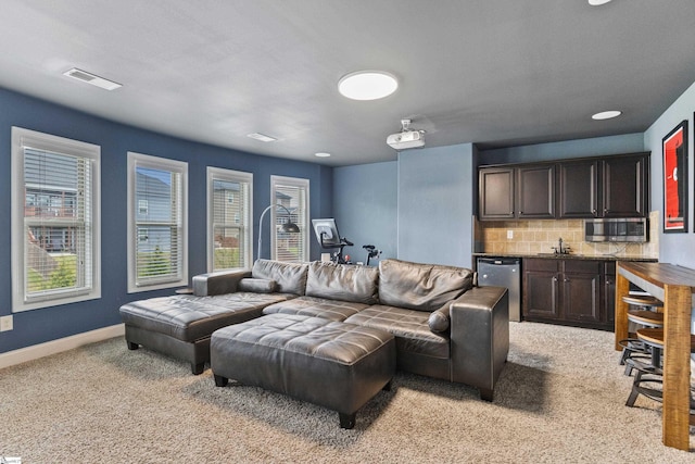 living area featuring plenty of natural light, baseboards, visible vents, and light colored carpet