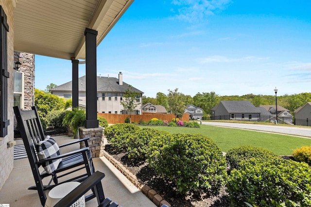 view of patio featuring fence, a porch, and a residential view