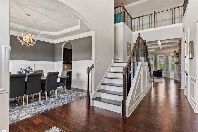 entrance foyer featuring a chandelier, stairway, a decorative wall, and hardwood / wood-style floors
