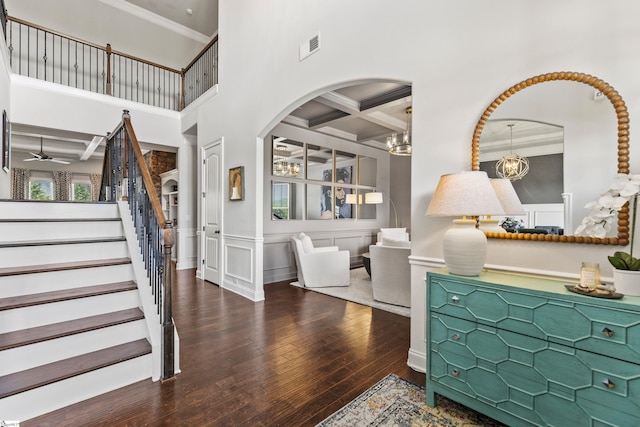 entryway featuring coffered ceiling, arched walkways, beamed ceiling, hardwood / wood-style flooring, and stairs