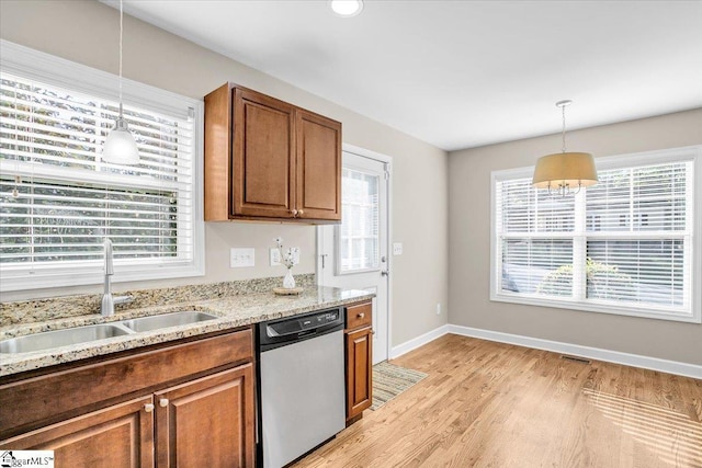 kitchen with decorative light fixtures, brown cabinets, stainless steel dishwasher, and a sink