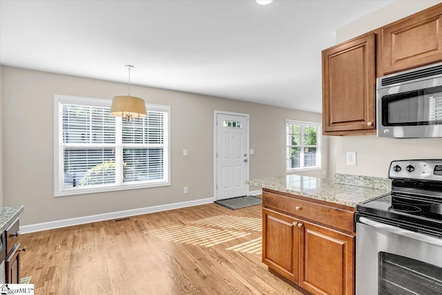 kitchen with light wood-style flooring, visible vents, pendant lighting, brown cabinets, and appliances with stainless steel finishes