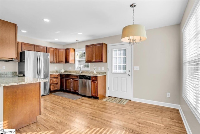 kitchen featuring stainless steel appliances, light wood-style flooring, plenty of natural light, and hanging light fixtures