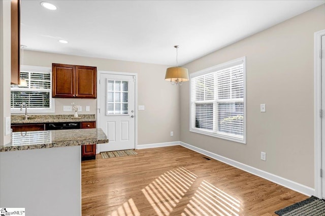 kitchen with a sink, pendant lighting, light wood finished floors, baseboards, and recessed lighting