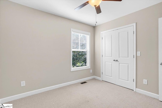 unfurnished bedroom with ceiling fan, visible vents, baseboards, and light carpet