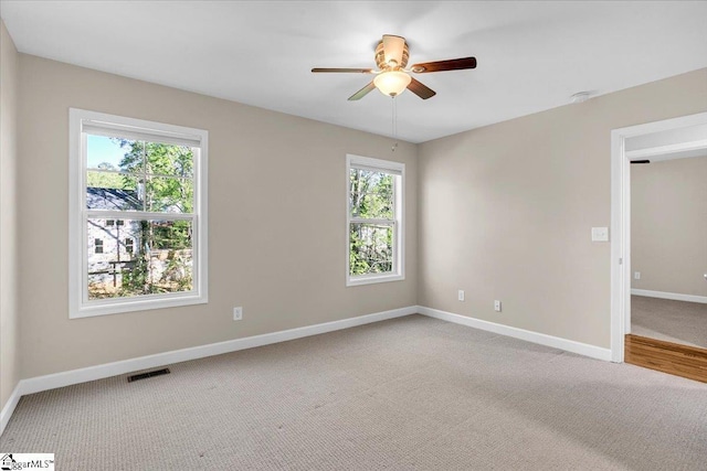 empty room with baseboards, visible vents, light colored carpet, and ceiling fan