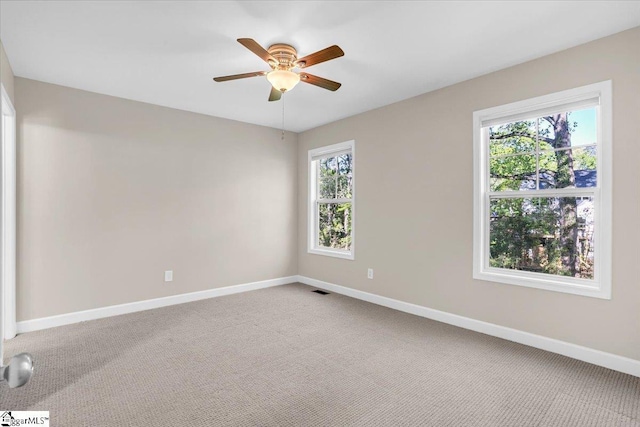 carpeted spare room featuring ceiling fan and baseboards