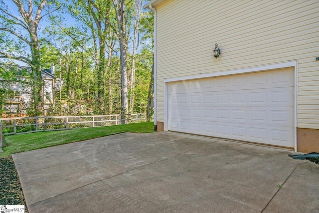 garage with concrete driveway and fence