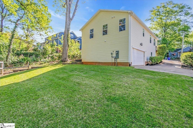 back of house featuring an attached garage, a lawn, and driveway