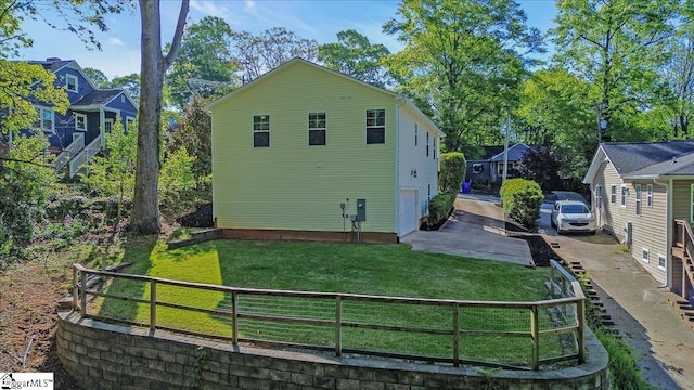 view of side of home with a garage, a yard, concrete driveway, and fence