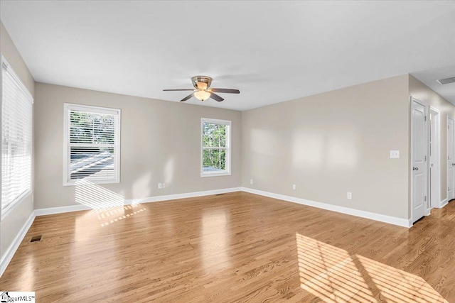 spare room with light wood finished floors, a ceiling fan, baseboards, and visible vents