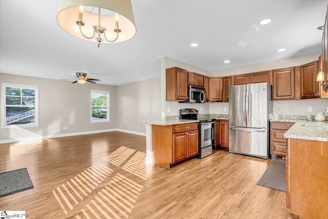 kitchen with brown cabinets, stainless steel appliances, light wood finished floors, and plenty of natural light