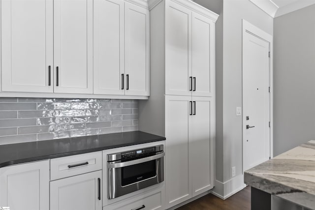 110 N Markley St Unit 304, Greenville, SC 29601 - kitchen with dark stone counters, decorative backsplash, oven, white cabinetry, and dark wood-style flooring
