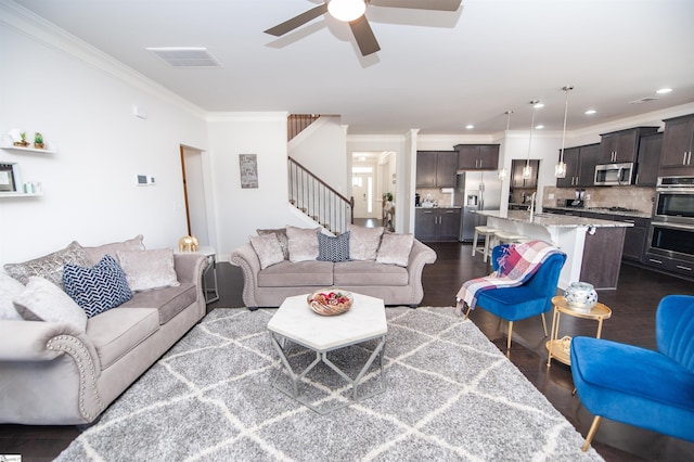 living room featuring dark wood finished floors, crown molding, stairs, and a ceiling fan