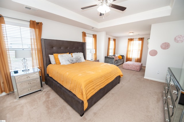 bedroom with light colored carpet, crown molding, a tray ceiling, and visible vents