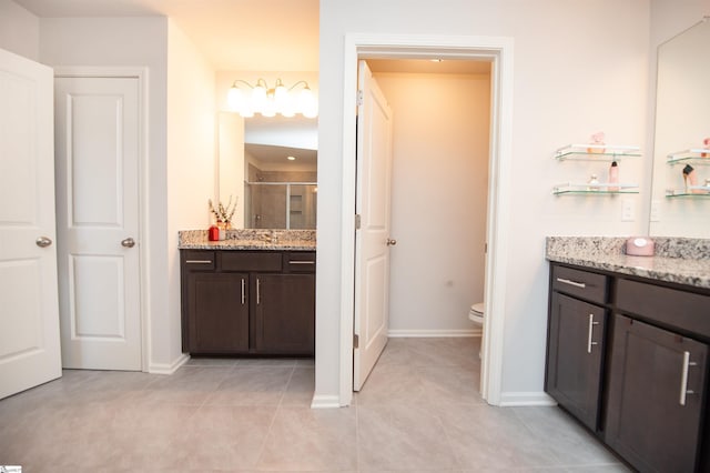 bathroom featuring a shower stall, toilet, vanity, and tile patterned floors