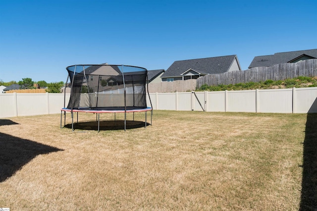 view of yard with a trampoline and a fenced backyard