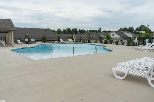 pool featuring a residential view, a patio, and fence