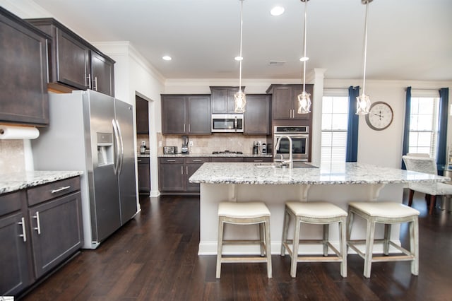 kitchen with crown molding, appliances with stainless steel finishes, a kitchen breakfast bar, and a sink