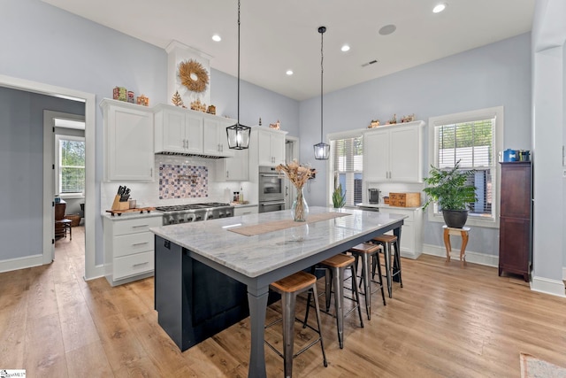 1359 Martin Creek Rd, Seneca, SC 29678 - kitchen featuring light wood finished floors, white cabinets, appliances with stainless steel finishes, a kitchen island, and a breakfast bar area