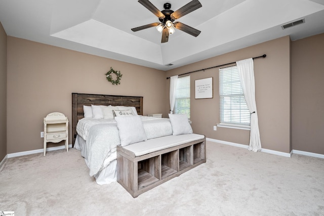 bedroom featuring a raised ceiling, baseboards, visible vents, and light colored carpet