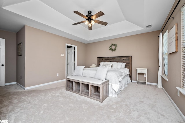 carpeted bedroom featuring a raised ceiling, visible vents, a ceiling fan, and baseboards
