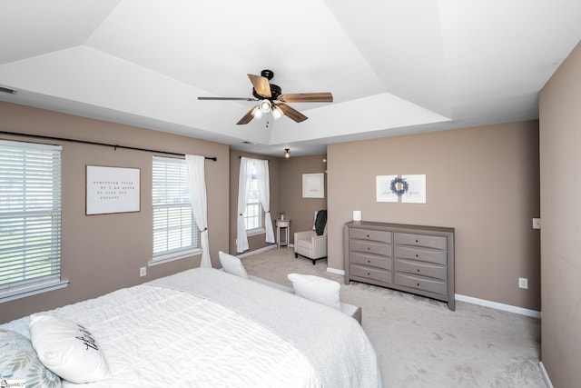 bedroom with light carpet, a tray ceiling, visible vents, and baseboards