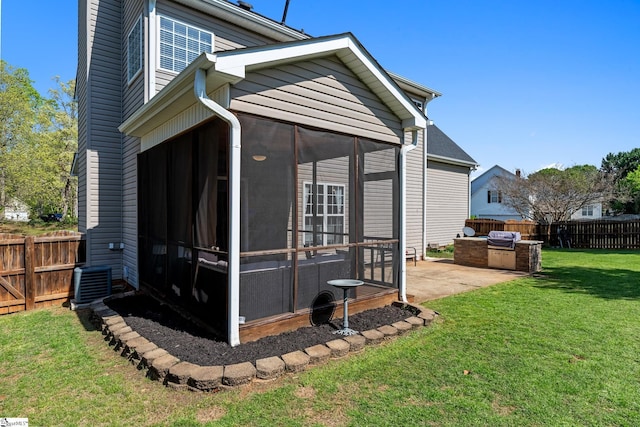 view of home's exterior featuring area for grilling, a fenced backyard, a patio area, a lawn, and a sunroom