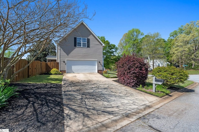view of side of home featuring an attached garage, driveway, and fence