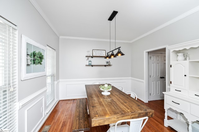 dining room with dark wood-style flooring, a wainscoted wall, visible vents, and crown molding